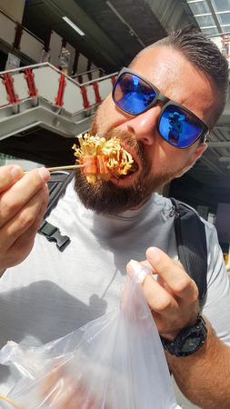 Male tourist eating thai street food in Bangkokの写真素材