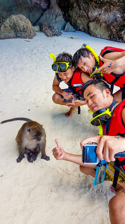 MONKEY BEACH, THAILAND - AUGUST 19, 2017 - Asian tourists taking selfie with monkey on Monkey Beach in Thailand on August 19, 2017のeditorial素材