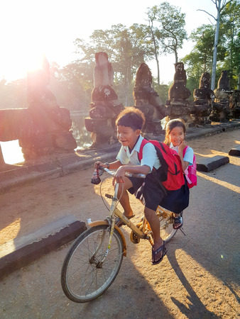 Siem Reap, Cambodia - DECEMBER 29, 2017: Two cambodian children in uniforms going to school by bikeのeditorial素材