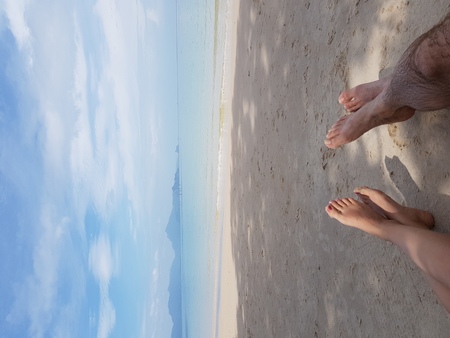 Couple with crossed legs on the beachの写真素材