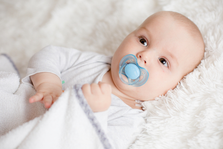 Few months old baby boy on soft white blanketの写真素材