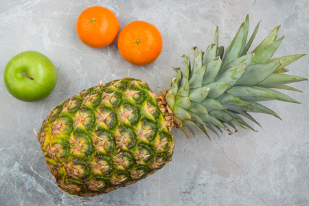 Pineapple, mandarines and apple on the stoneの写真素材