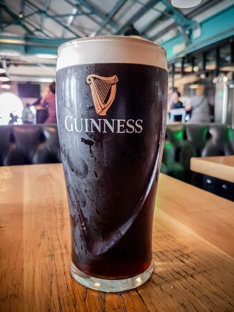 DUBLIN, IRELAND - August 4th, 2019: A pint of Guinness stout on the table with blurry bar in backgroundのeditorial素材