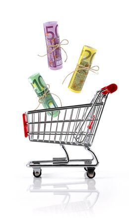 Shopping cart toy with euro bills falling into it against white background isolated, concept of spending moneyの写真素材