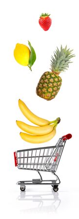 Shopping cart toy with fruit falling into it against white background isolatedの写真素材