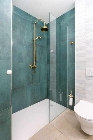 Shower and toilet in summer apartment bathroom with green tilesの写真素材