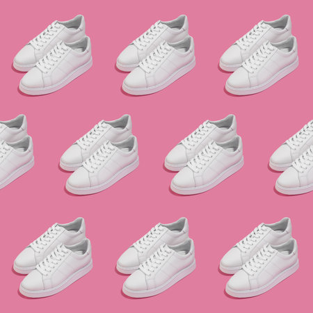 Repeating pattern of a pair of white female sneakers on pink backgroundの写真素材