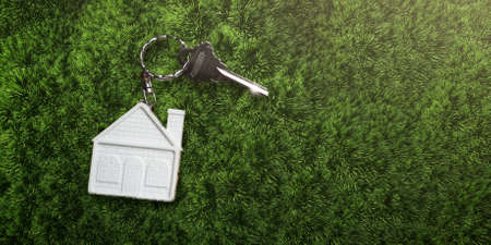 House keys with house shaped keychain, on a grass backgroundの写真素材