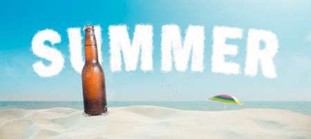 A view of a bottle of beer on the beach with blue sky with background lettersの写真素材