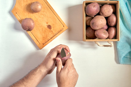 Hands peeling potato on a white table 1の写真素材