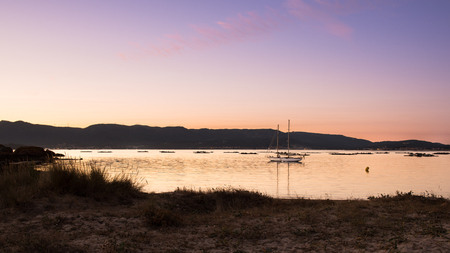 landscape with a sailboat sailing at sunset on the shores of an island Galicia, Spainの写真素材