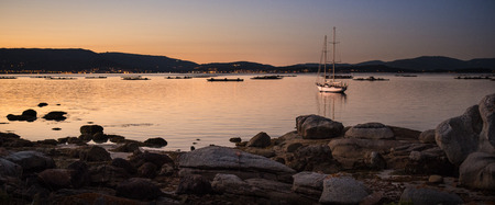 landscape with a sailboat sailing at sunset on the shores of an island Galicia, Spainの写真素材
