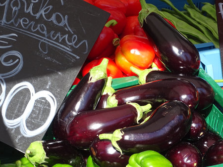 Fresh egg plants and tomatoes on display at a farmers market.の写真素材