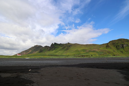 Iceland-On the black beach by the small town of VÃ­k Ã­ MÃ½rda with the church in the backgroundの写真素材