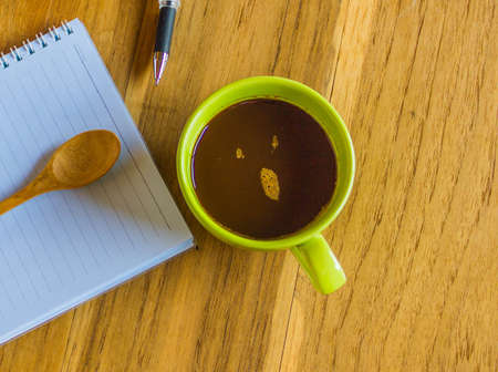 Office table with notepad and pen, cup of coffee and coffee spoonの写真素材