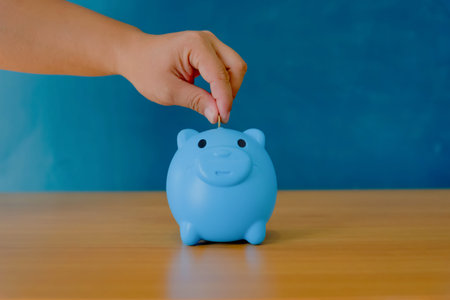 Savings concept. Hand putting coin in the piggy bank
