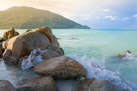 Splash waves hit rocks with the beautiful sunlight and sky .の写真素材