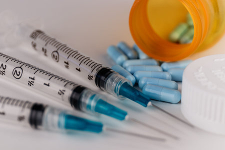 Close up view of a syringe with hypodermic needle and generic blue pills. Opiate and heroin...