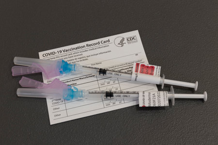 Indianapolis - Circa November 2021: Moderna COVID-19 Vaccination booster syringes or hypodermic needles and Vaccination Record Card. COVID-19 boosters have been recommended for all adults.のeditorial素材