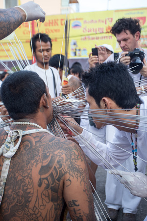 PHUKET, THAILAND - SEPTEMBER 29: An unidentified devotee of a Chinese shrine gets pierced on his mouth with sharp weapon to take part in the 2014 Phuket Vegetarian Festival on September 29, 2014 in Phuket, Thailandのeditorial素材