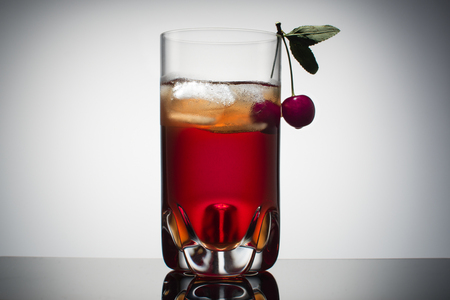 Homemade fresh cherry juice in transparent glass with ice and fresh cherry. Gradient background.の写真素材
