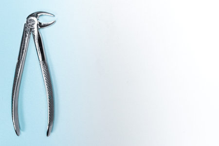 Used real dental forceps from dental equipment tools. Light blue background with copy space.