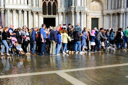 VENICE, ITALY - SEPTEMBER 12, 2017 - Tourists and locals make their way along the St. Mark's Basilica walls through the flooded St. Mark Square. Piazza San Marco, Veniceのeditorial素材