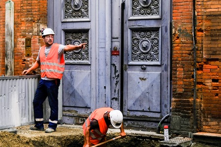 TOULOUSE, FRANCE - AUGUST 10, 2018 - Two road workers on the street. First gives instructions, and second digs a pit.のeditorial素材