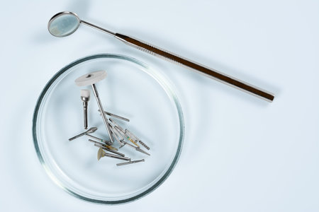 Dental medical tools, dentist equipment: stomatological mirror and used dental burs in Petri dish...