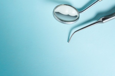 Dental mirror and explorer on blue light background with copy space, close-up.の写真素材