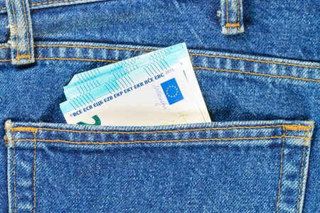 Several bills of twenty euros in the back pocket of jeans. Concept of absentminded person, potential victim of theft.の写真素材