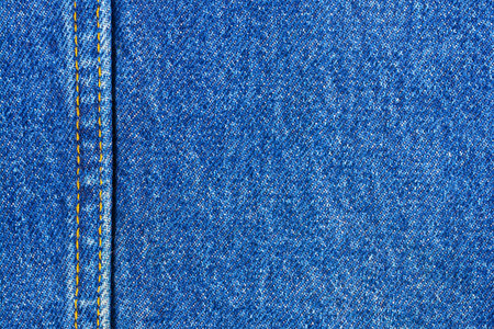 Jeans background denim pattern with yellow seam. Classic dark blue stonewashed fabric texture....