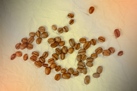 Coffee beans on vintage crumpled paper background, some roasted coffee beans.