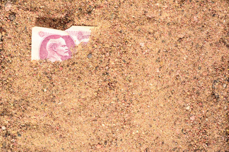 Old Soviet banknote of 25 rubles lies is not needed by anyone covered with sand. USSR, portrait of Lenin, close-up.の写真素材
