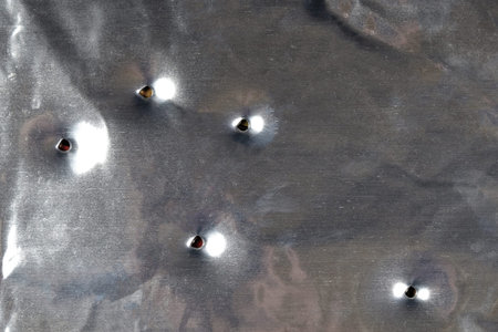 Fragment of metal sheet from the car with bullet holes. Background and texture