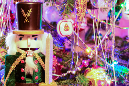 Nutcracker soldier under decorated colorful Christmas tree. Traditional Xmas festive wooden toy,...