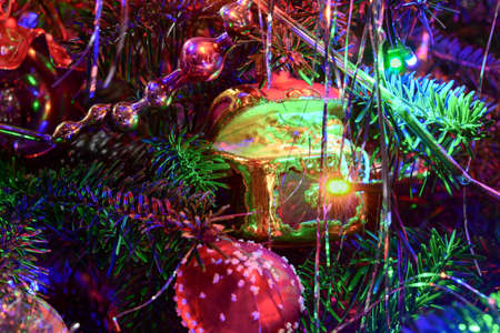 Christmas tree holiday background with glass toys, garland, balls, lights. Colorful decoration close-up in dark key.の写真素材