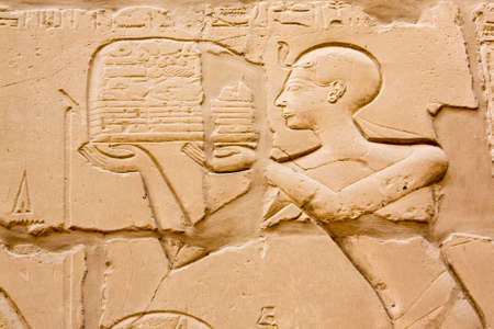 Karnak Temple Complex in Luxor, Egypt. An ancient bas-relief with hieroglyphics on the wall, the pharaoh brings an offering to the gods.の写真素材