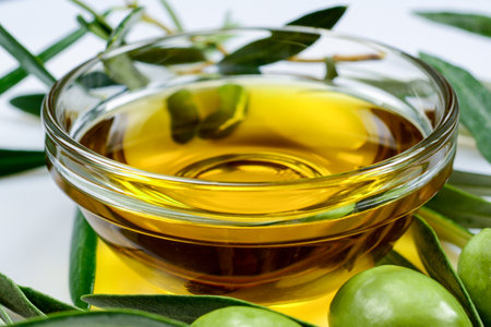 Olive oil. Glass transparent bowl with greek extra virgin olive oil among olive leaves and olives. Close up macro, high resolution.の写真素材