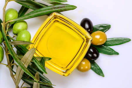 Olive oil. Greek olive oil in square glass transparent bowl with fresh and marinated olives and leaves. Close up, Isolated on white background.の写真素材