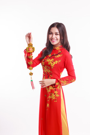 Beautiful Vietnamese woman with red ao dai holding lucky decorate object for celebrate lunar new year on white backgroundの写真素材