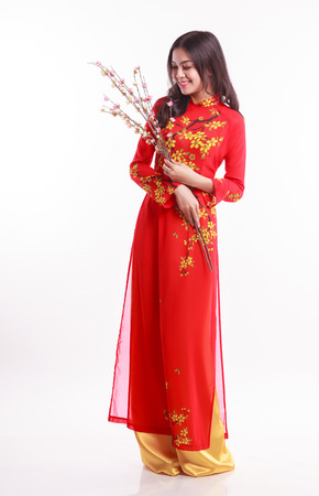 Beautiful Vietnamese woman with red ao dai holding cherry blossom for celebrate lunar new year on white backgroundの写真素材