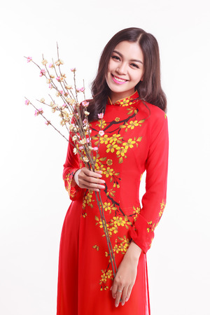 Beautiful Vietnamese woman with red ao dai holding cherry blossom for celebrate lunar new year on white backgroundの写真素材