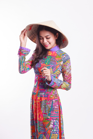 Beautiful Vietnamese young woman with tradition modern ao dai and palm-leaf conical hat ( non la ) on white backgroundの写真素材