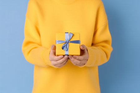 Woman holding gift box on color background, closeup. Christmas celebrationの素材