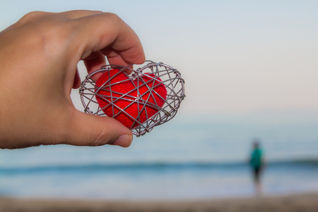 Hand that holds a strong red heart backdrop is the sea.の写真素材