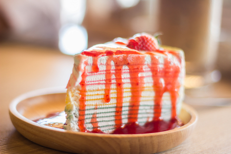 Crape cake dessert topped with sauce strawberry on wooden plate.の写真素材