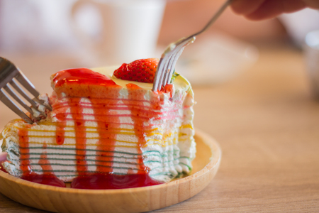 Crape cake dessert topped with sauce strawberry on wooden plate.の写真素材
