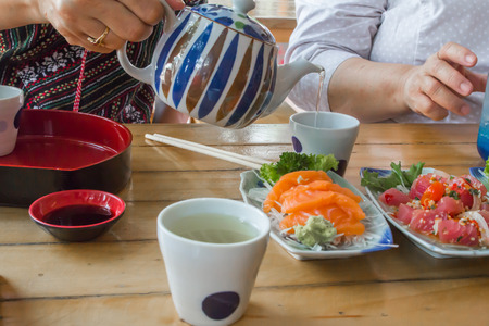 People are pouring hot green tea to eat with raw fish.の写真素材