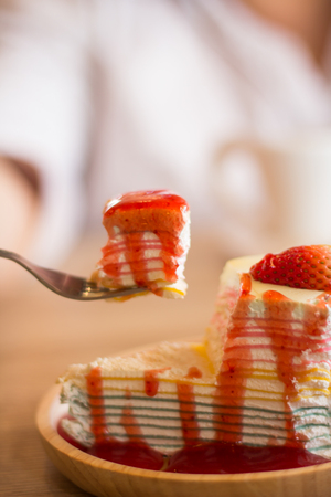 Crape cake dessert topped with sauce strawberry on wooden plate.の写真素材